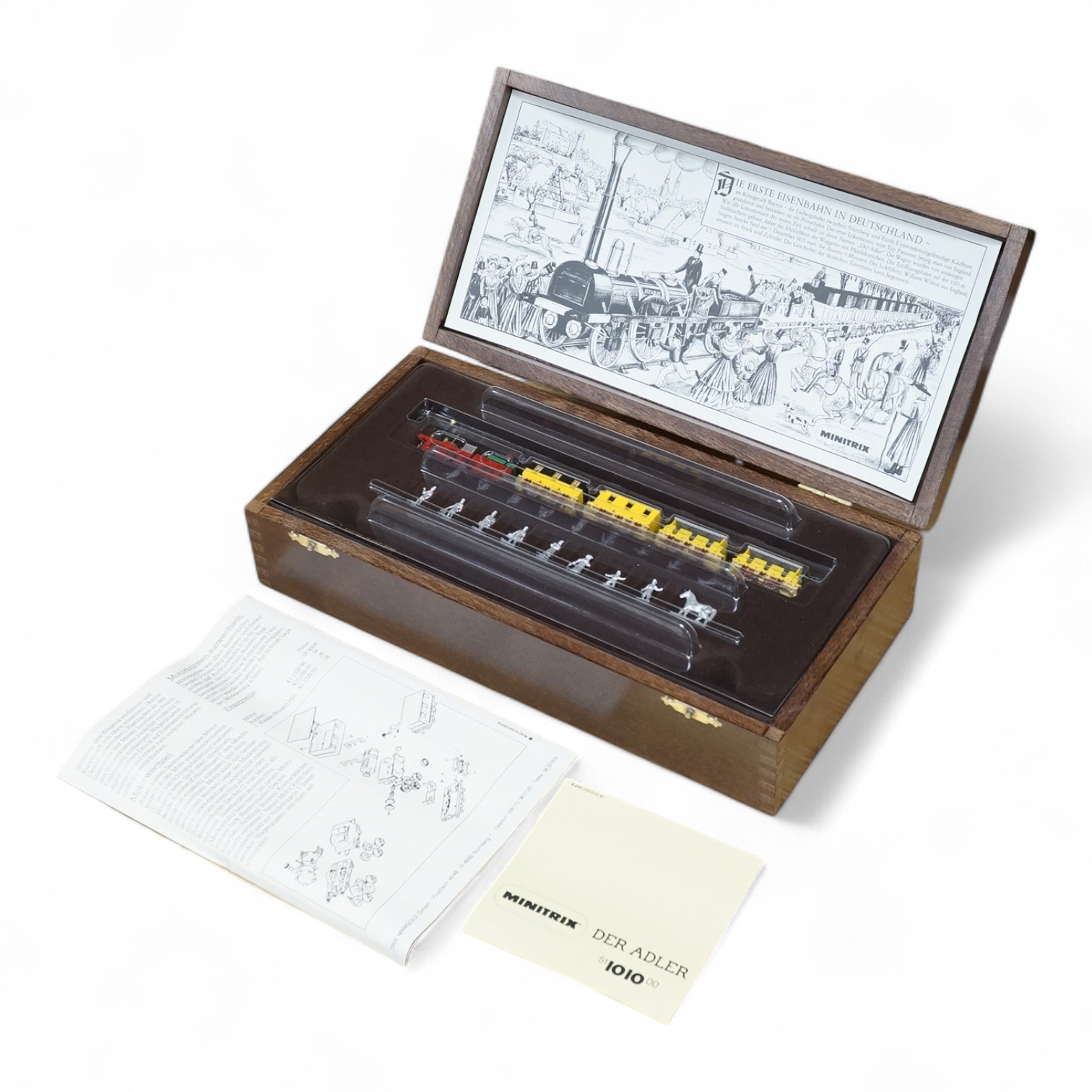 A Minitrix Der Adler German N gauge railway train set, comprising of a mid 19th century 2-2-2 tender locomotive, four coaches and white metal line side figures, and contained within a wooden case with information leaflet